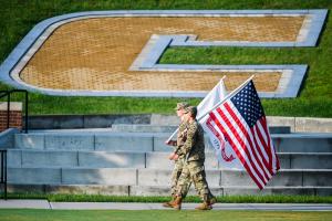 Two ROTC cadets with flags in front of the Power C