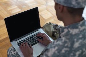 African american student in military camouflage on his laptop