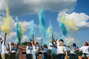 Students throwing blue and yellow powder into the air