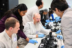 Researchers working on small machines at a table
