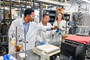Engineers in lab coats working with scientific instruments in a lab.