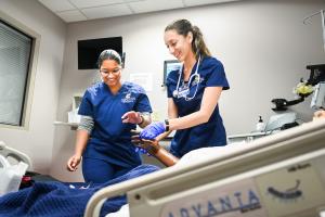 Two UTC nursing students practicing clinical skills on a mannequin