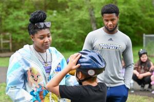Two UTC students are standing and talking to a child wearing a blue helmet