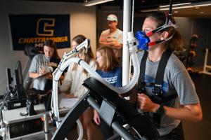 UTC student running on a treadmill wearing a breathing mask