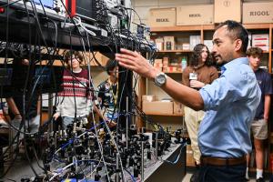 A man in front of quantum computing equipment, speaking to students