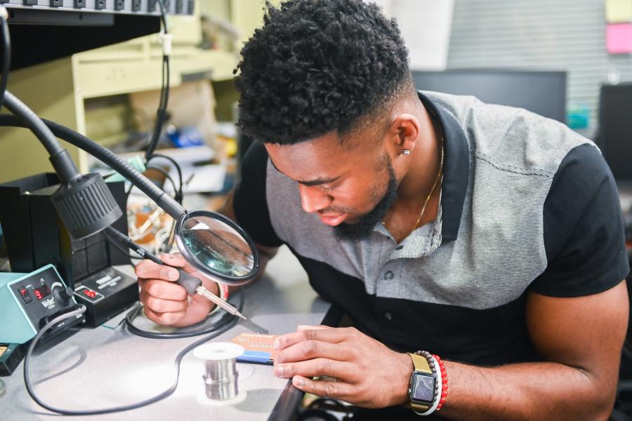 Student soldering with a microscope 