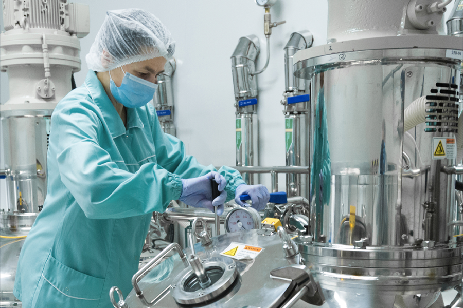 Female chemical engineering student working in a lab in a lab coat, head covering, mask and gloves. Female chemical engineering student working in a lab in a lab coat, head covering, mask and gloves.