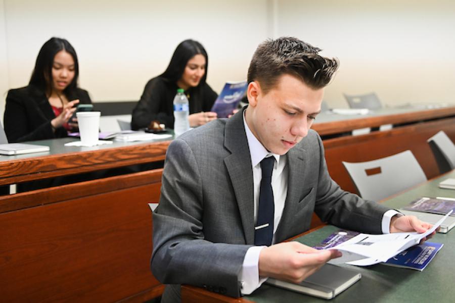 Student wearing suit and tie reading a document