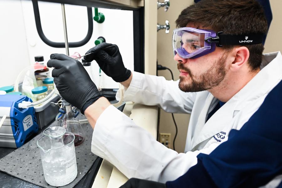UTC Quality Academics UTC student working in a lab wearing a white coat and safety goggles