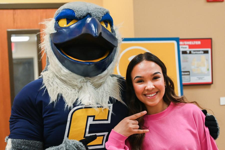 Blue and Gold Preview Day Potential UTC student holding up the Power C hand gesture standing next to Scrappy