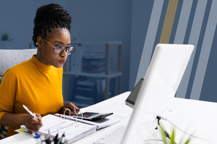 Woman sits in front of a computer and calculator taking notes.