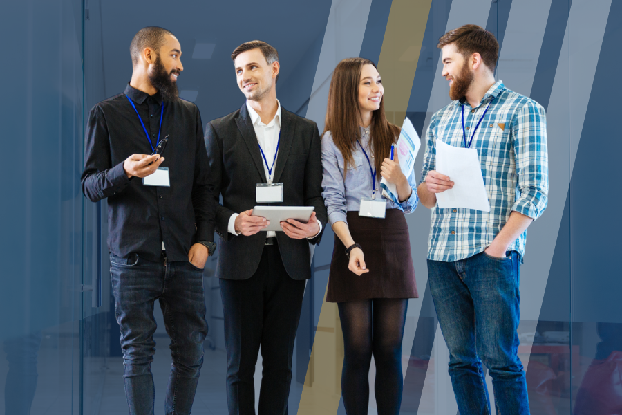 Four young professionals stand in a hallway discussing business. 