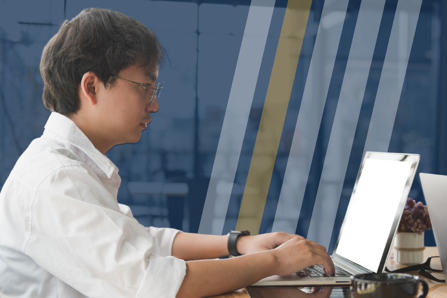 Man types on a computer in an office setting.