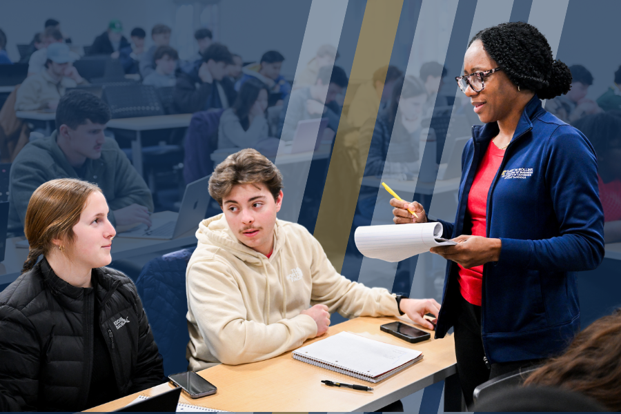 Professor Brown holds a notepad and pencil as she speaks with two RCOB students during an Economics course. 