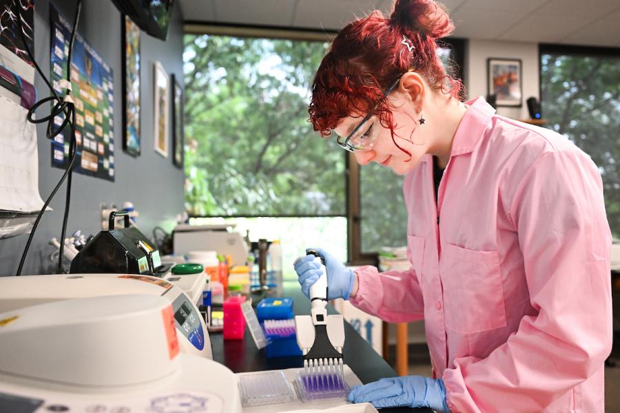 UTC student wearing goggles and lab protective gear while using lab equipment