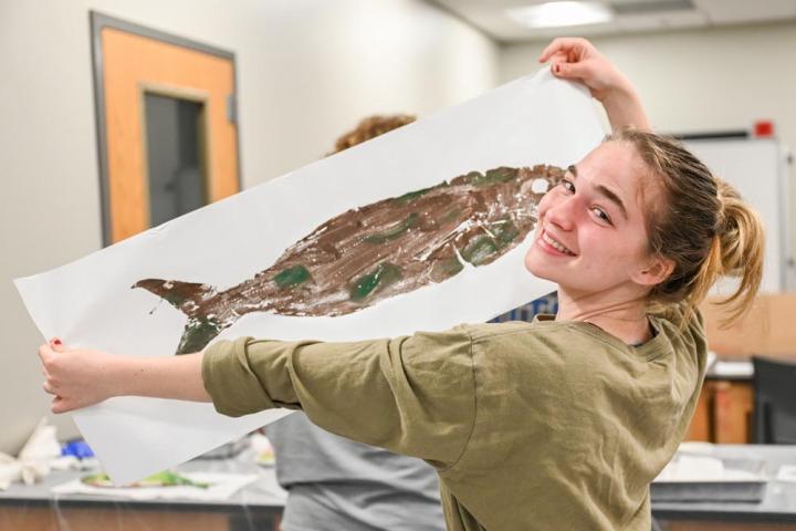 Honors student holds up art from her Amazing Biology of Fishes class.