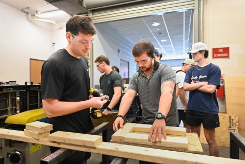 UTC students measuring and screwing bolts into a wood structure